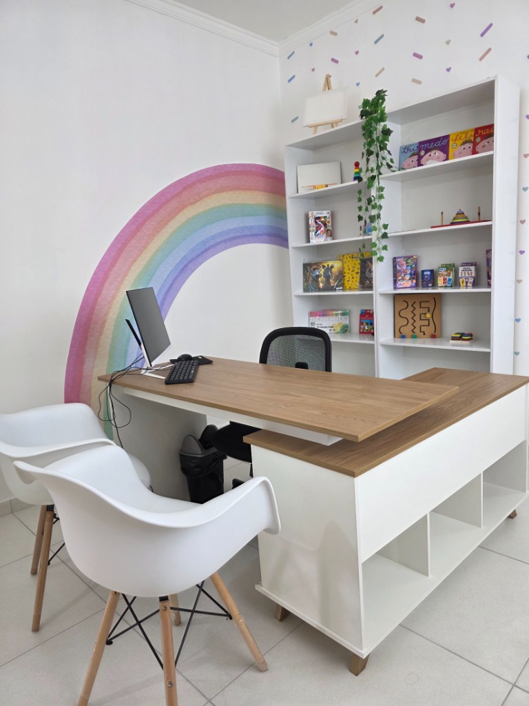 Mesa de atendimento infantil com arco-íris na parede